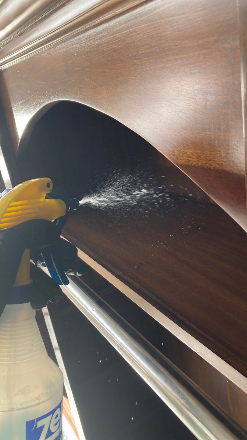 Technician spraying cleaning solution on smoke-damaged wood furniture